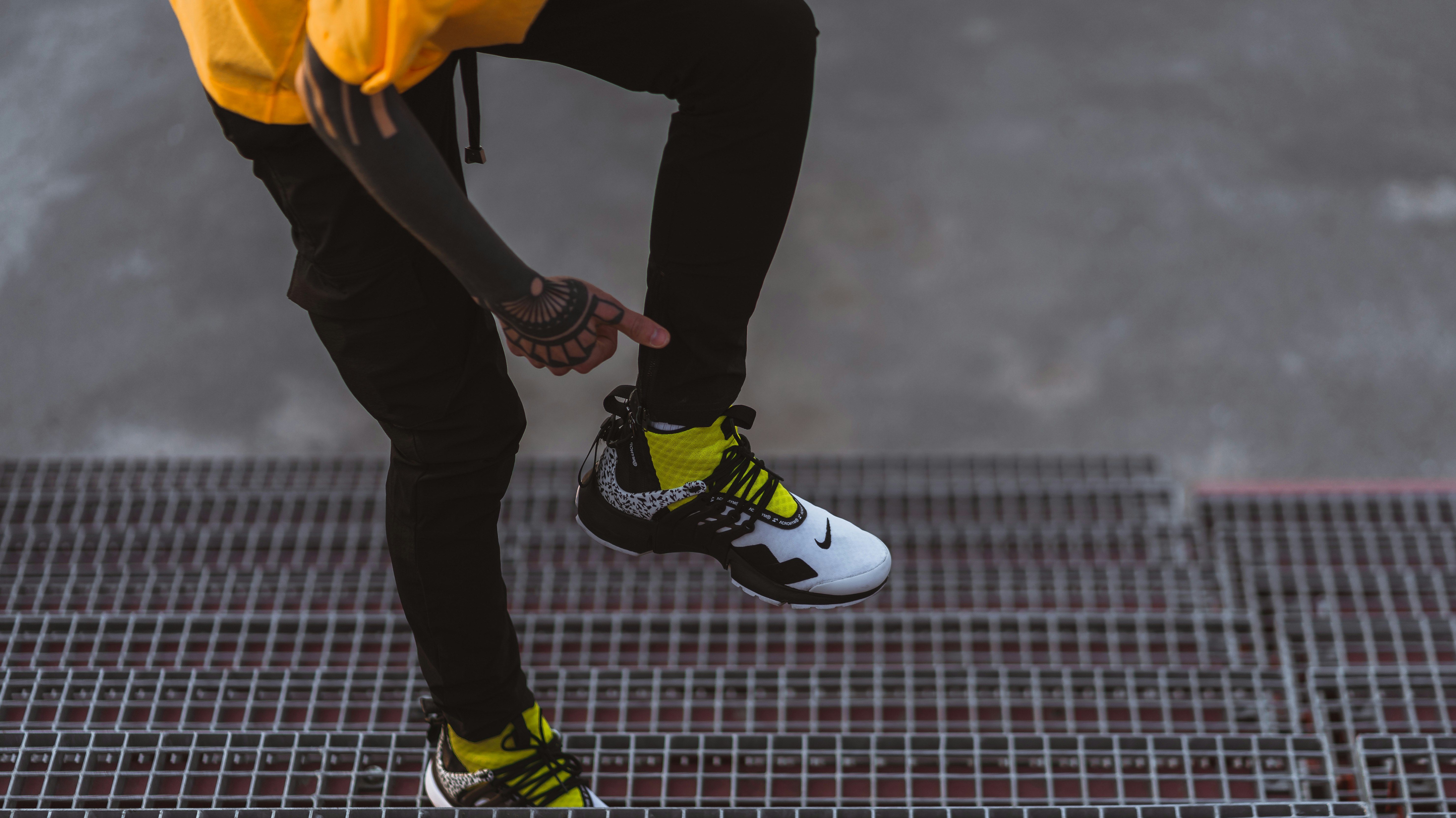 person in black pants wearing black and white nike sneakers